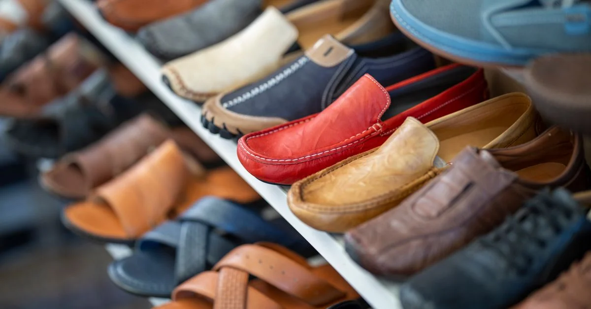 Une variété de chaussures en cuir colorées soigneusement disposées sur une étagère d'exposition.