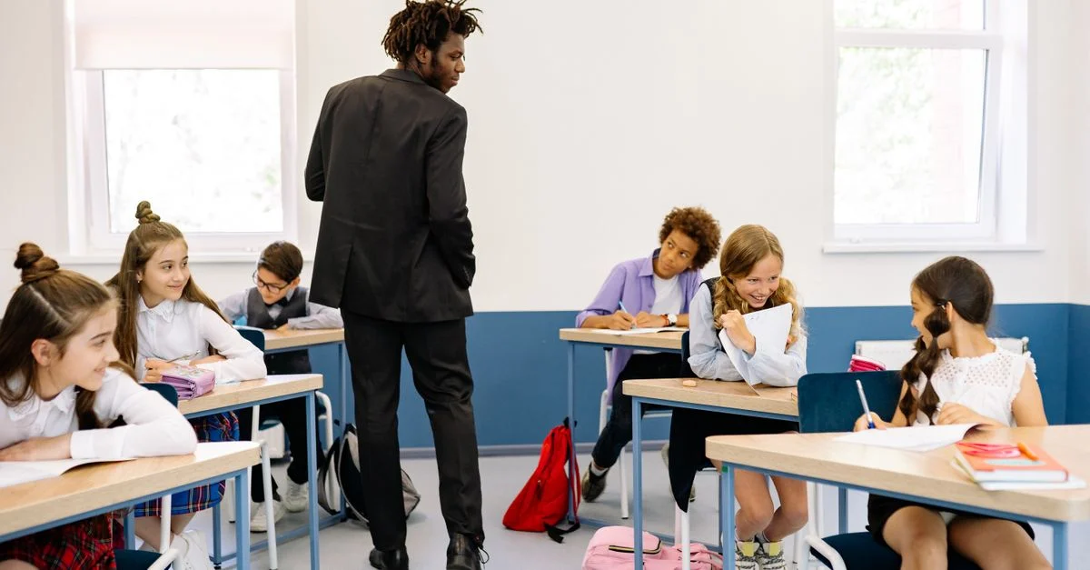 Un enseignant surveille des élèves engagés dans des activités en classe par une belle journée.