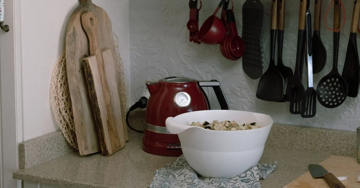 Un plan de travail de cuisine confortable avec des ustensiles, une bouilloire et un bol d'ingrédients frais.