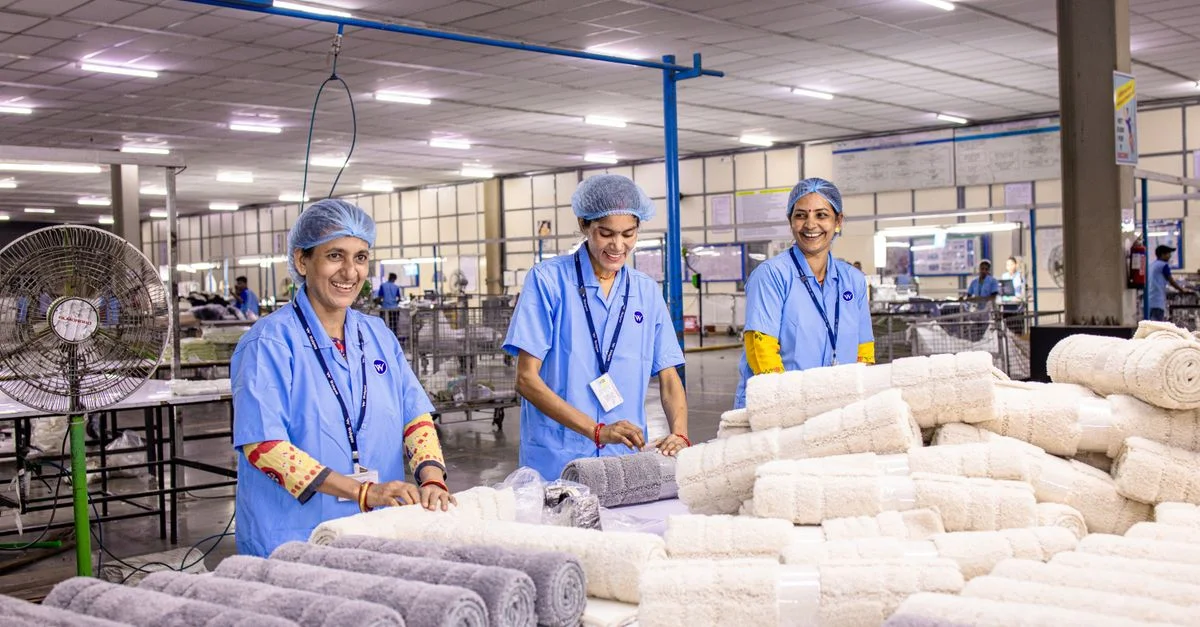Groupe d'ouvriers du textile disposant des serviettes dans une usine très éclairée.